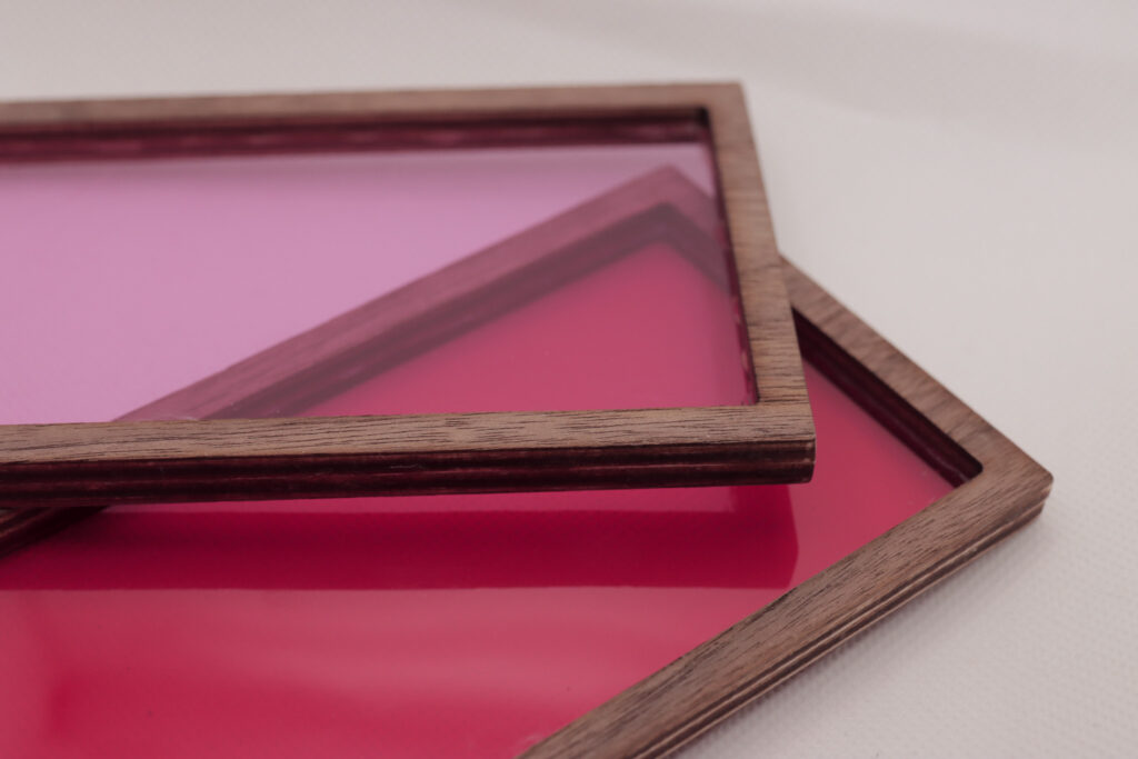 Two wooden frames with shades of pink inserts laid on each other 