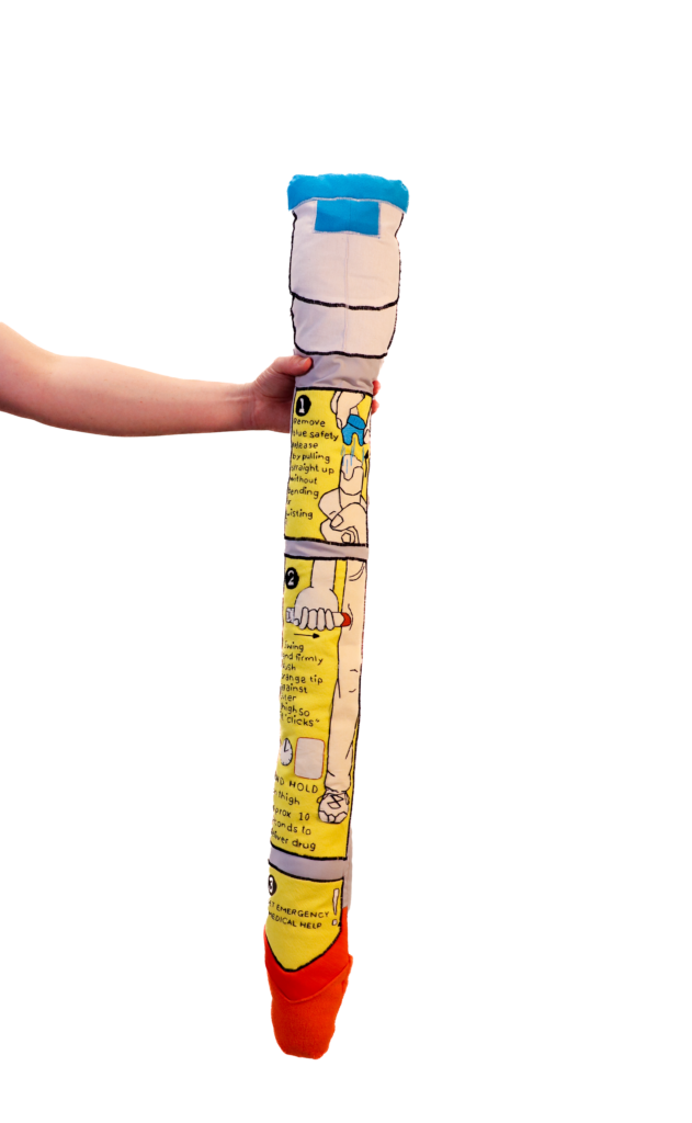 Arm holding out large stuffed Epi-pen sculpture, blank background